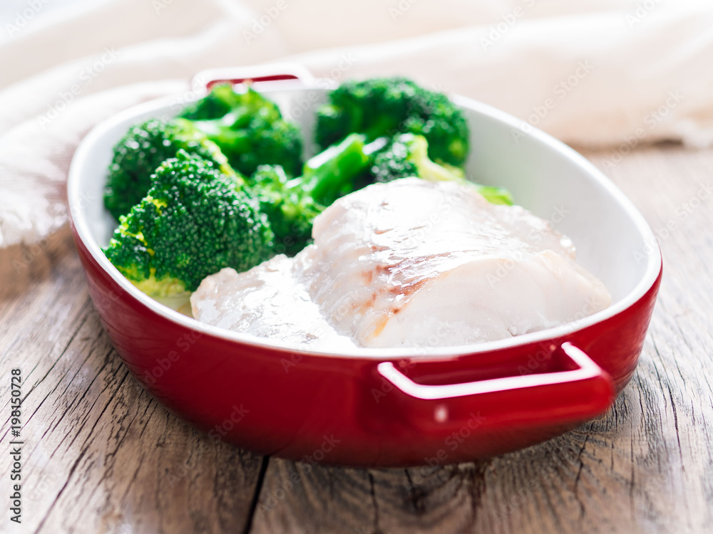 Fish cod baked in the oven with broccoli - healthy diet healthy food. Rustic wooden brown background, side view, selective focus.