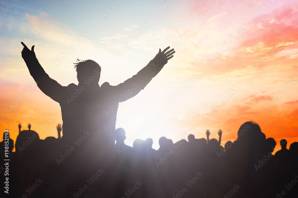 Believers worship and commemorate Easter concept: group of silhouettes people worshiping God on sunset sky background