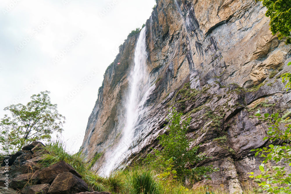 Waterfall and huge rock. Valley of waterfalls in Lauterbrunnen, Switzerland.