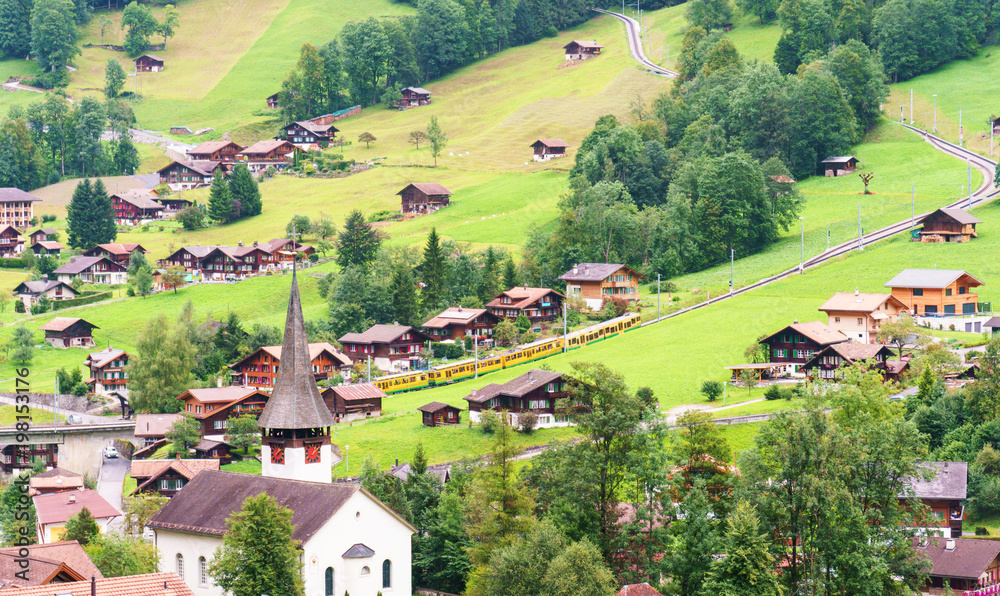 Lauterbrunnen landscape with a church an rack railway with trains going up. Switzerland.