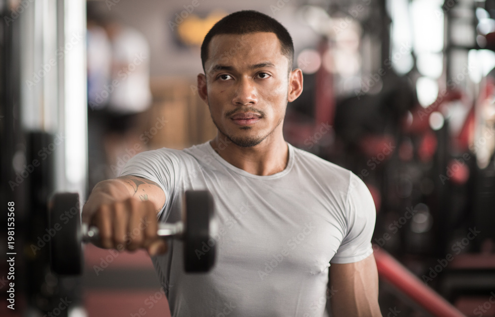 Muscular builder man training his body with dumbbell in Modern fitness center Muscular builder man training his body with dumbbell in Modern fitness center