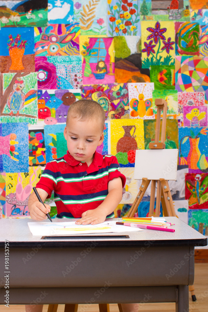 Fototapeta premium Little artist. Colorful wall with paintings in background.