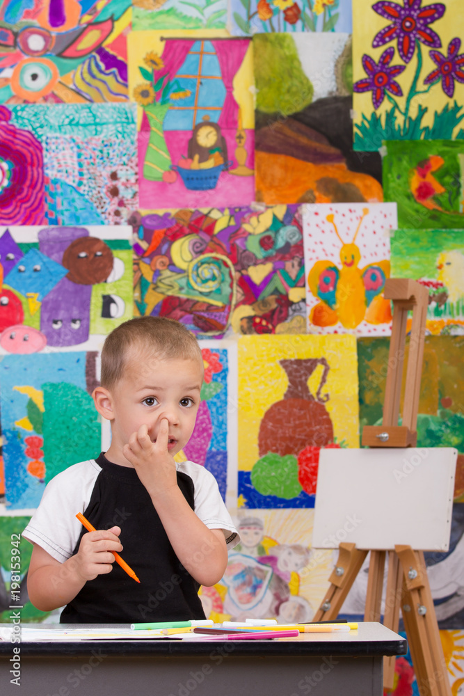 Fototapeta premium Little artist. Colorful wall with paintings in background.