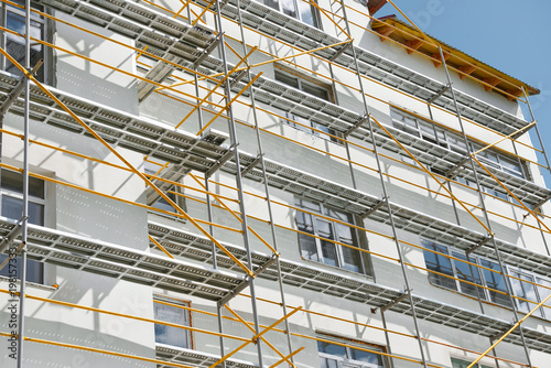scaffolding near a new house, building exterior, construction and repair industry, white wall and window, yellow pipe © soleg