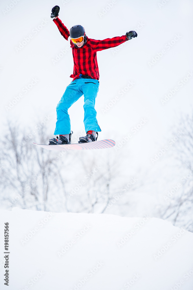 Picture of sportive man snowboarder jumping on snowy hill