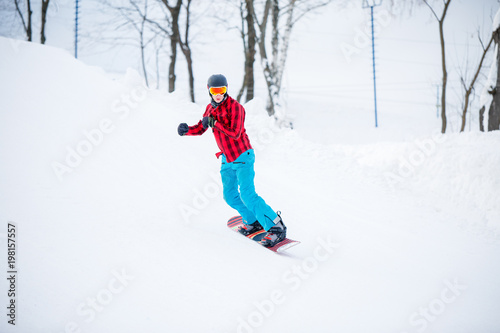 Image of sportive snowboarder man riding on snowy hill