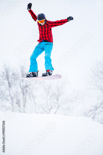 Picture of sportive man snowboarder jumping on snowy hill