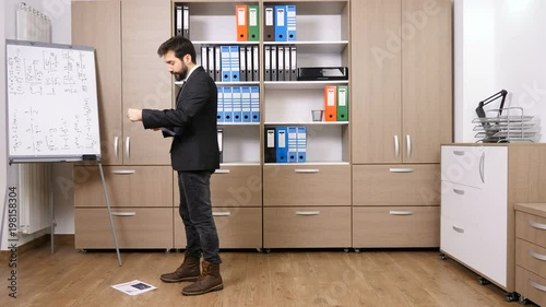 Stressed businessman throwing papers from a folder on the floor in his office, Full body shoot
