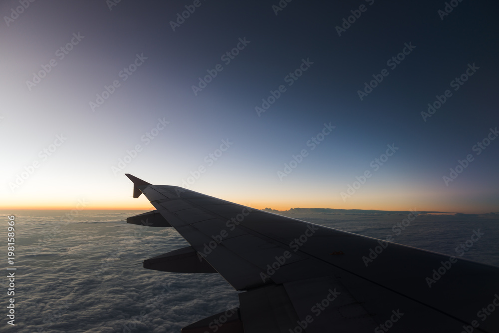 The plane is flying through the sunset sky