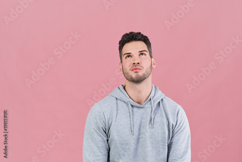athletic attractive man in a hoodie looking up with wistful reminiscing expression. Concepts of choice, decision, memories