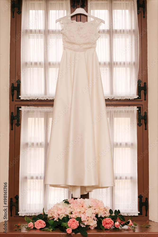 Beautiful White Wedding Gown Hanging by Window Beautiful White Wedding Gown Hanging by Window