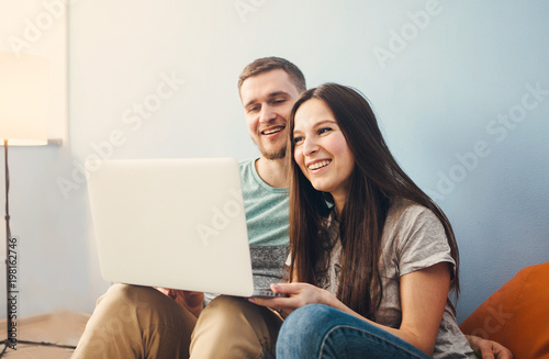 Young couple sitting at home and  using laptop, surf the Internet.