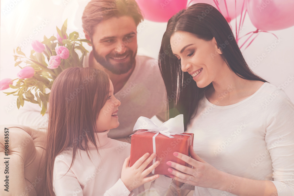 It is so pretty. Amazing careful intrigued woman holding a lovely box while being greeted on mothers day by her family It is so pretty. Amazing careful intrigued woman holding a lovely box while being greeted on mothers day by her family