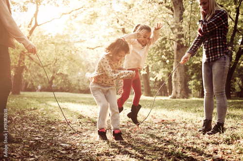 Cheerful family playing with jump rope together in park. photo