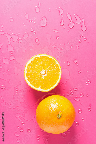 Ripe Juicy Whole and Halved Orange on Fuchsia Pink Background with Water Drops. Vitamins Healthy Diet Summer Detox Vegan Superfoods Concept. Poster Banner Template. Copy Space Flat Lay