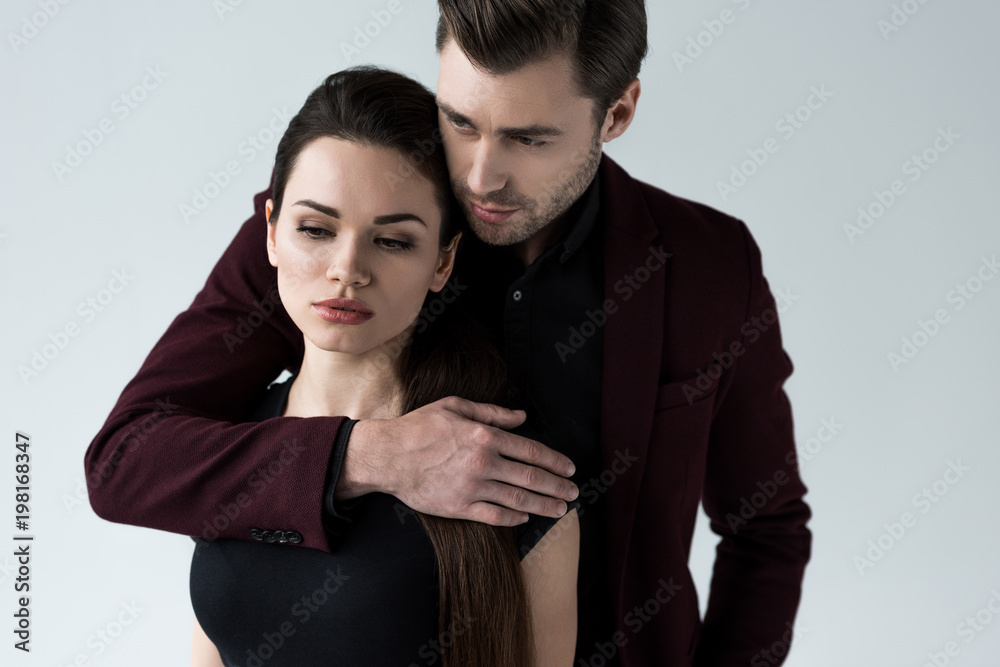 handsome man hugging his attractive girlfriend, isolated on grey handsome man hugging his attractive girlfriend, isolated on grey