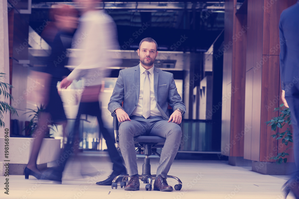 Obraz premium business man sitting in office chair, people group passing by
