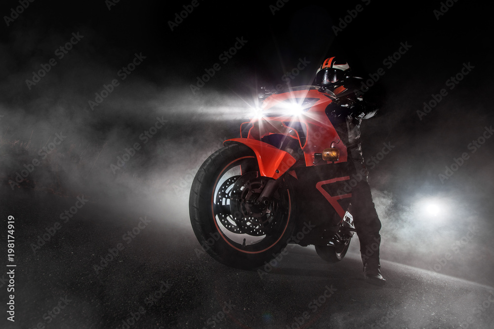 Supersport motorcycle driver at night with smoke around