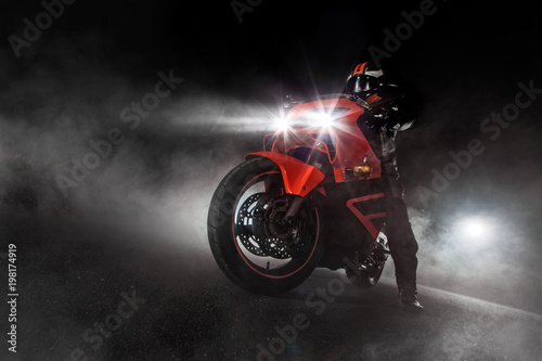 Supersport motorcycle driver at night with smoke around