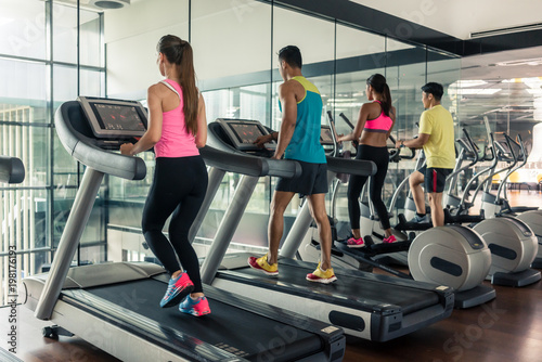 Full length rear view of a fit active woman running on treadmill during high-intensity cardio session in a trendy fitness club with modern equipment