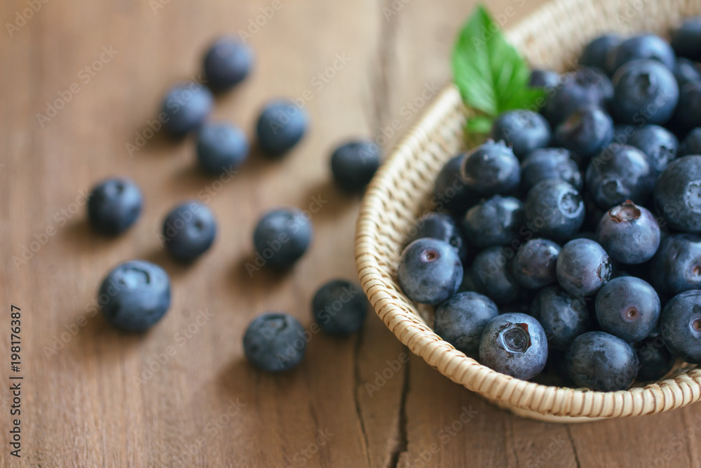 Fresh wild blueberries in wooden basket put on wood table with copy space for background, selective focus. Blueberry is healthy and delicious fruits which have high antioxidant and vitamin C. Fresh wild blueberries in wooden basket put on wood table with copy space for background, selective focus. Blueberry is healthy and delicious fruits which have high antioxidant and vitamin C.
