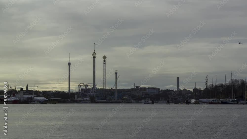 Timelapse of the ferryboats of Stockholm, Sweden, passing back and forth - with the amusement park Grona Lund - Gröna Lund - and other building along the coastline. Lots of sky - an angle with more wa Timelapse of the ferryboats of Stockholm, Sweden, passing back and forth - with the amusement park Grona Lund - Gröna Lund - and other building along the coastline. Lots of sky - an angle with more wa