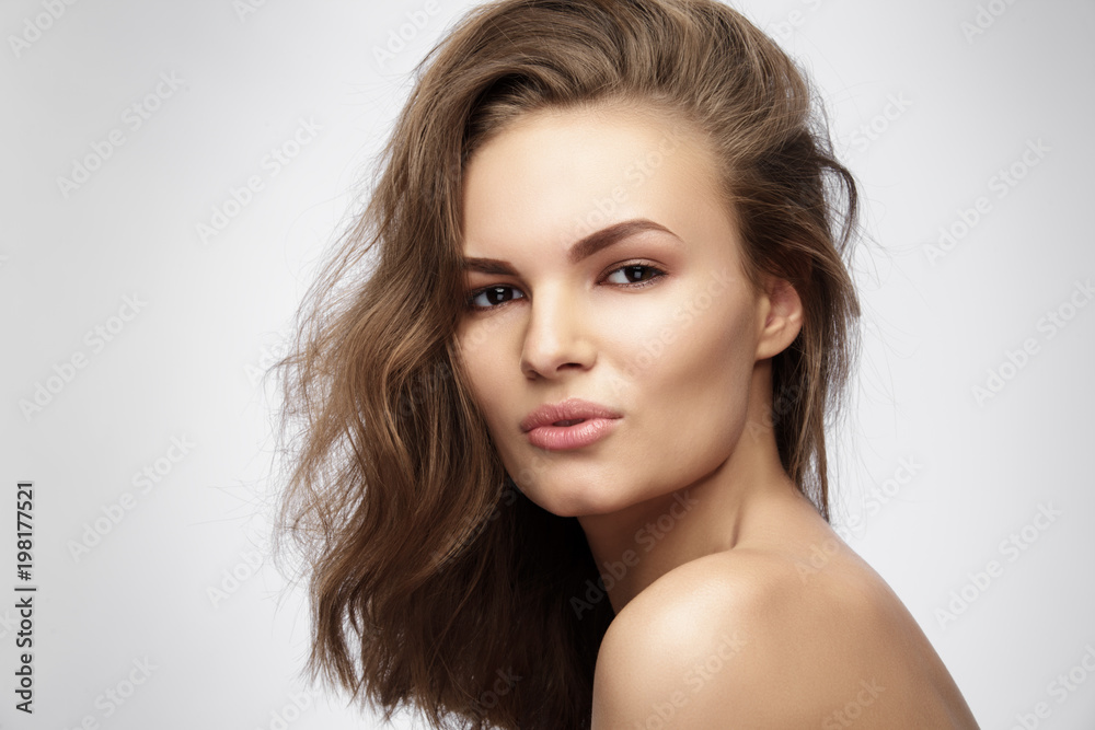 Fototapeta premium Beautiful young woman with long brown hair on gray background.