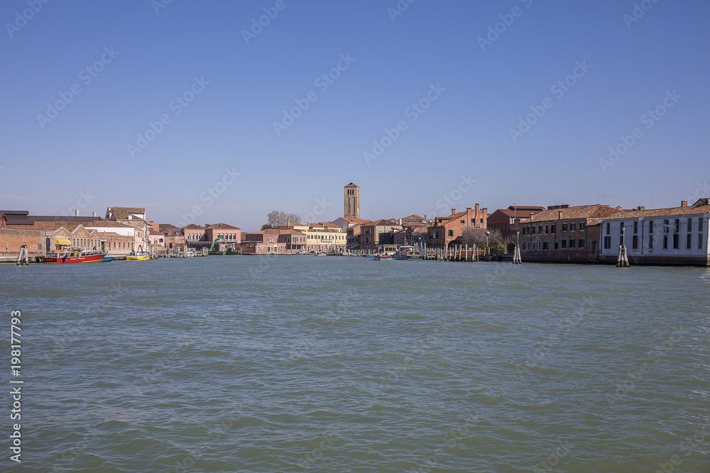 View on the island of Murano with its orange brick buildings and campanile from the Venice lagoon, Italy