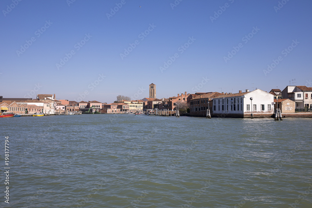 View on the island of Murano with its orange brick buildings and campanile from the Venice lagoon, Italy