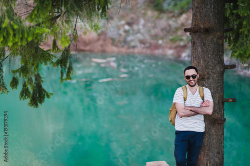 Fototapeta Naklejka Na Ścianę i Meble -  Bearded man model poses alongside a Green water Lake.