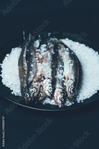 Close up of pile of salted fish in frying pan isolated on black photo