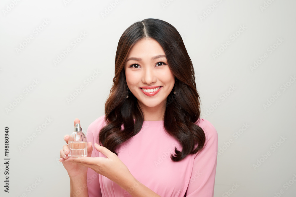 Beautiful asian woman holding a perfume bottle and applying it Beautiful asian woman holding a perfume bottle and applying it