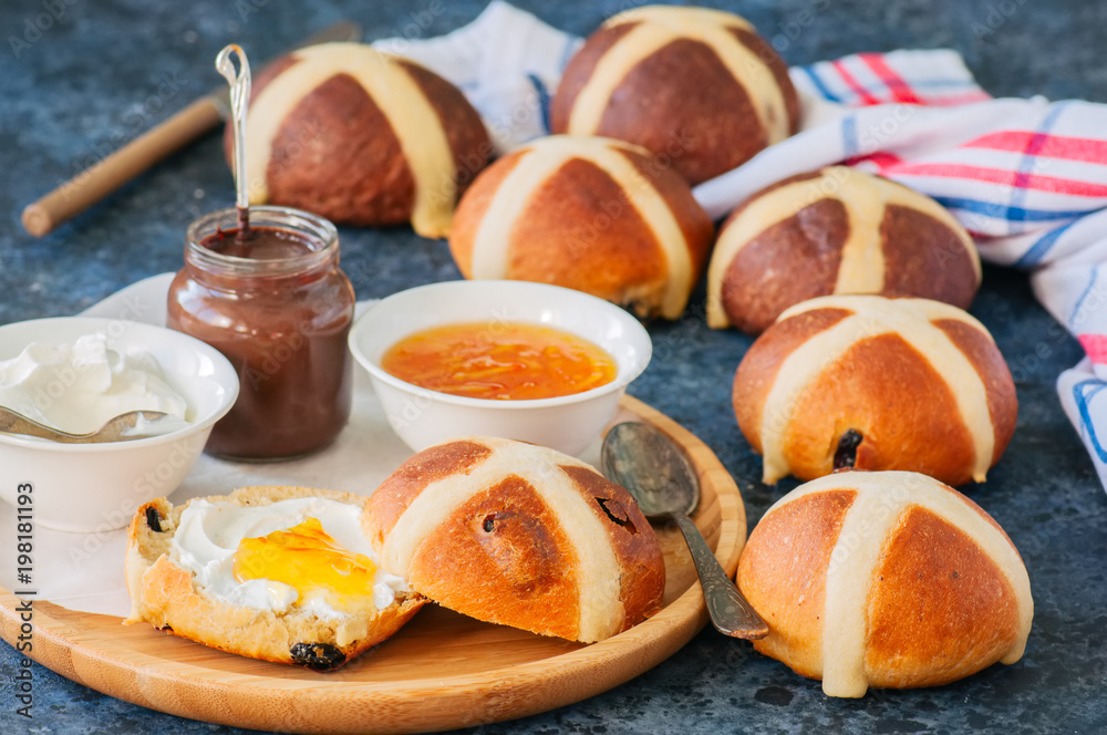 Homemade chocolate and classic hot cross buns with raisins on a blue stone background.