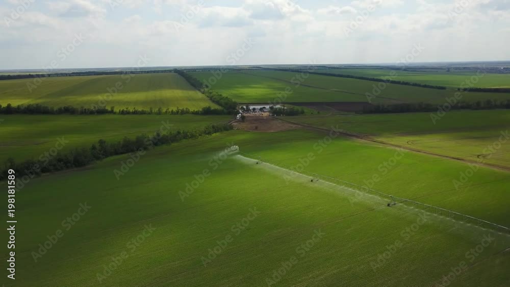 Modern automated irrigation equipment watering freshly seeded field. Irrigation of farmland to ensure the quality of the crop. Aerial view of internet connected irrigating machine in a wheat field