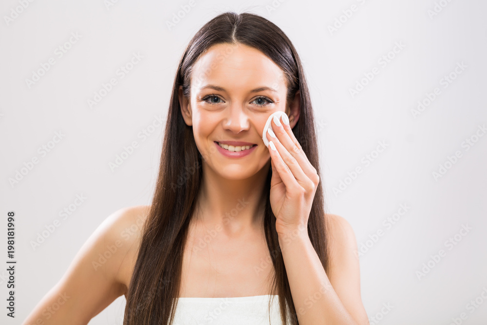 Beautiful brunette woman cleaning her face with cotton pad. Beautiful brunette woman cleaning her face with cotton pad.
