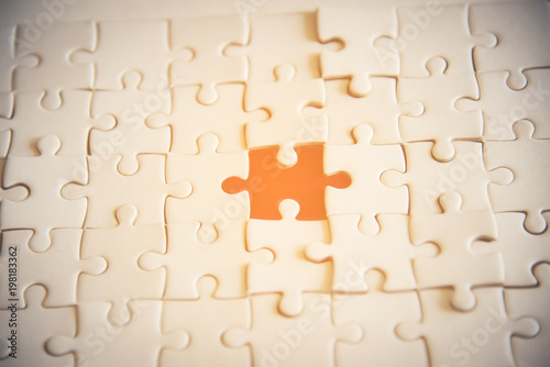 Jigsaw with one piece missing revealing orange background