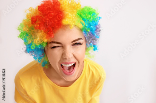 Young woman in funny disguise posing on light background. April fool's day celebration