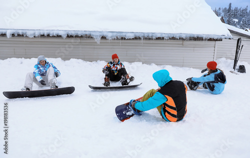 Group of friends taking snowboard lessons at snowy resort. Winter vacation photo