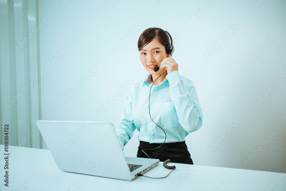 Portrait of beautiful young asian woman call center operator in headset with laptop computer at workplace. Portrait of beautiful young asian woman call center operator in headset with laptop computer at workplace.