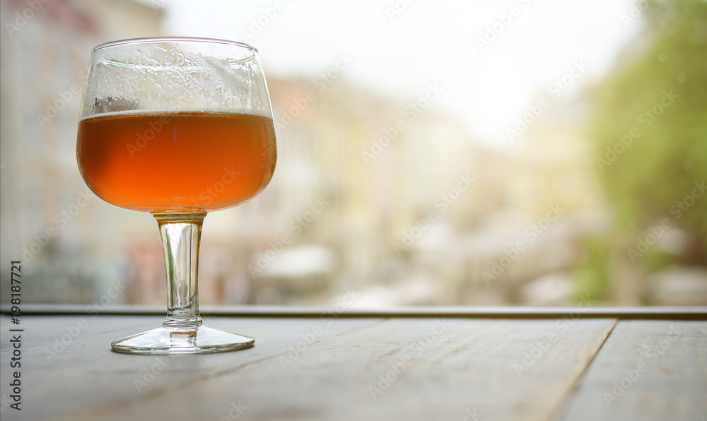A glass of beer on a wooden table by the window. Free space A glass of beer on a wooden table by the window. Free space