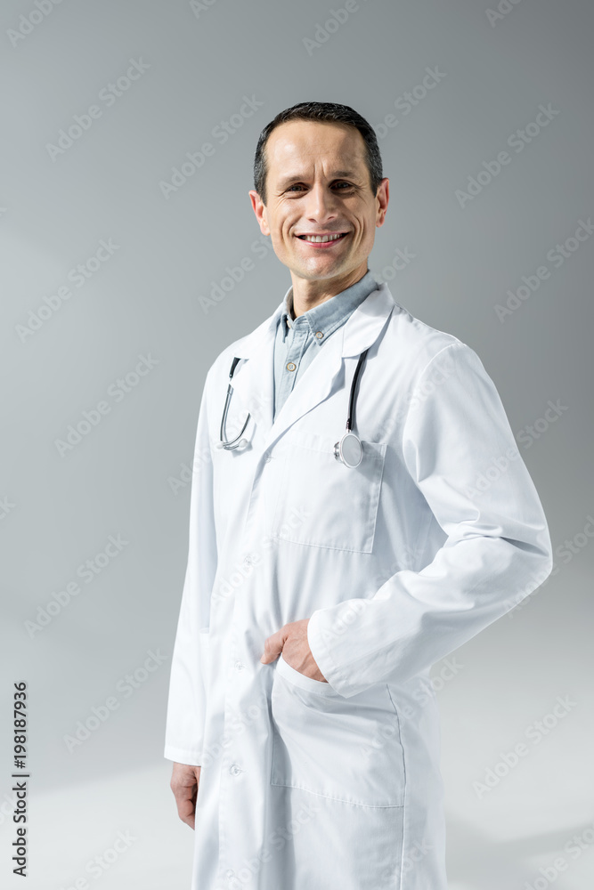 happy adult doctor in white coat looking at camera isolated on grey happy adult doctor in white coat looking at camera isolated on grey