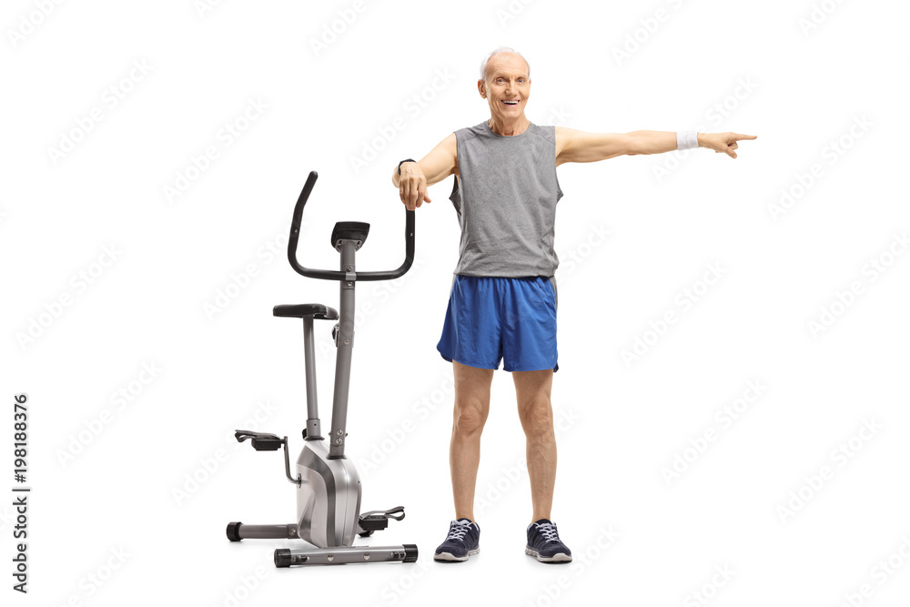 Senior leaning on an exercise bike and pointing
