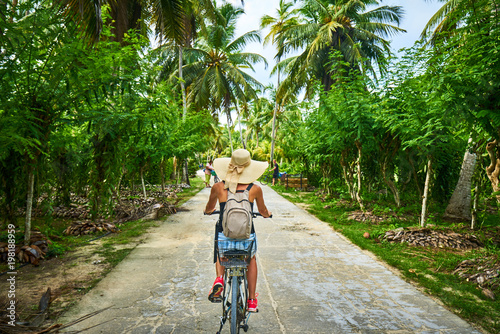 woman on a bicycle crosses vanilla plantations, dique island, se