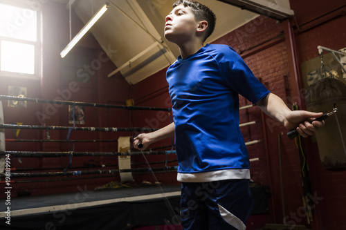 A young male boxer trains by doing sipping rope exercises in the gym before a fight photo