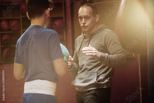 A young male boxers trains with his coach for a fight in the gym