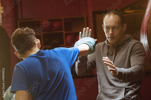 A young male boxers trains with his coach for a fight in the gym