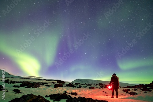  Woman with shining lamp in hand on the mountain viewing to the aurora borealis © Dirk