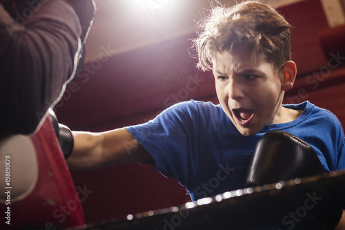 A young make boxer launching forwards while training for a fight in the ring