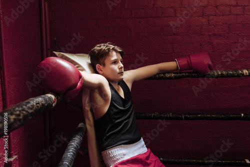 Young boxer taking a break on the ring during training to get his breath back