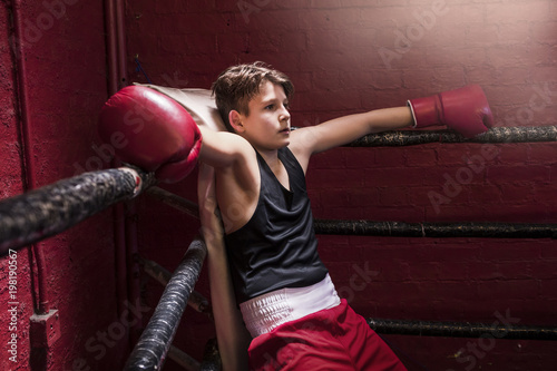 Young boxer taking a break on the ring during training to get his breath back